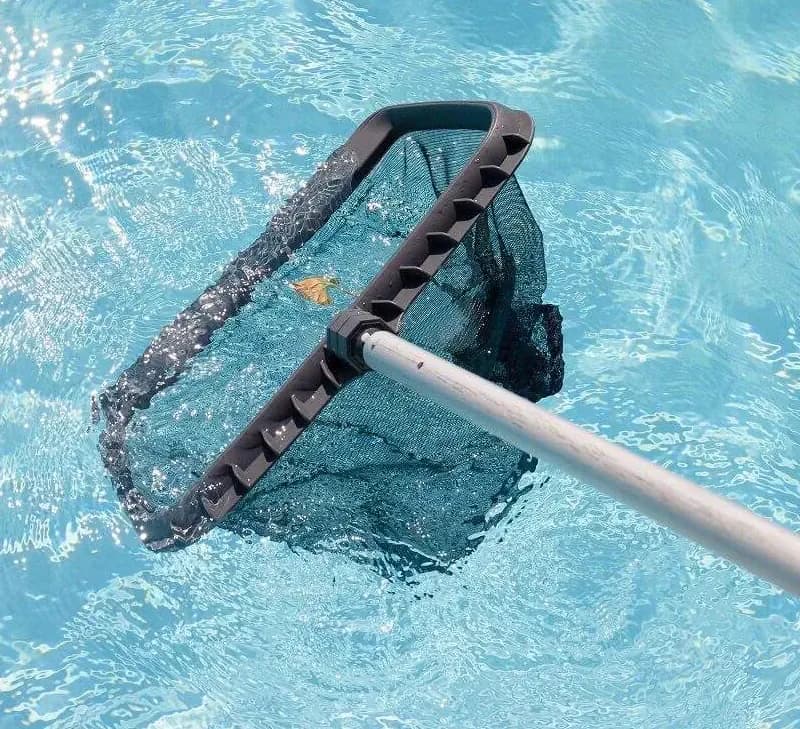 Pool net dipped slightly into the water.  There is a single leaf to be caught.